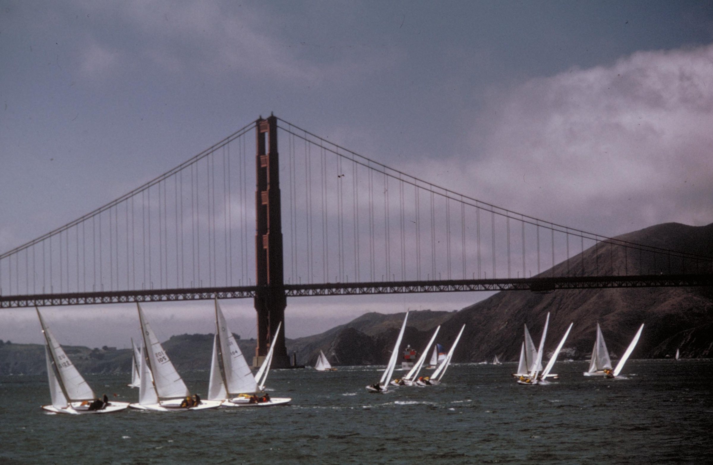 A fleet of sailboats racing on San Francisco Bay beneath the Golden Gate Bridge