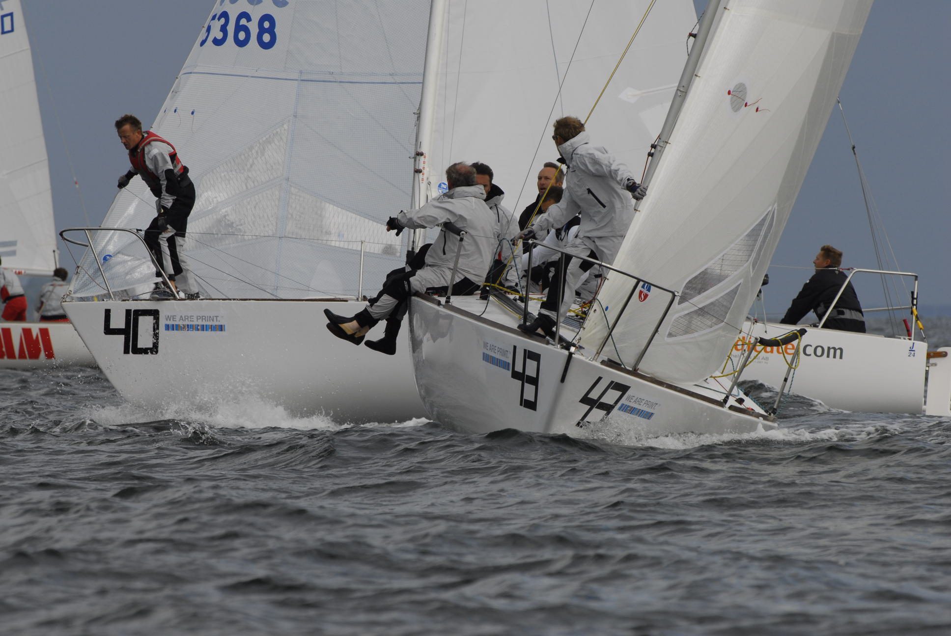 Crews hiking out on two J/24 keelboats racing close together